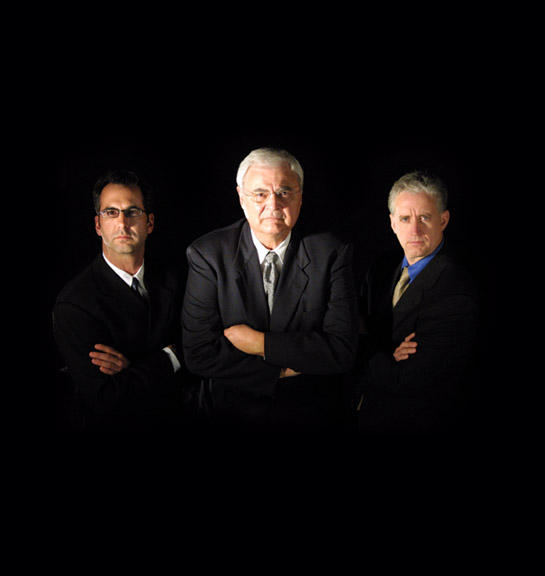 Three men in business suits standing with their arms crossed