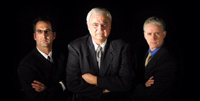 Three men in business suits standing with their arms crossed